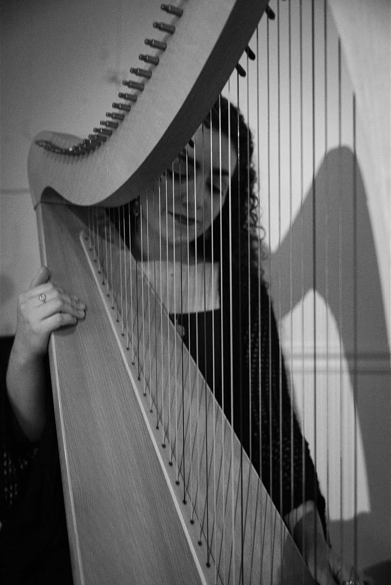 Christa Dalmazio behind the strings of her harp, black and white, at Ruah