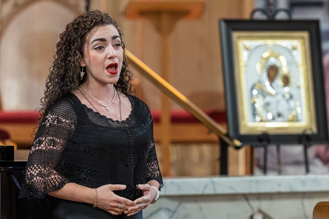 Christa Dalmazio singing beside a Marian icon at the Holy Family Hospital of Bethlehem benefit concert